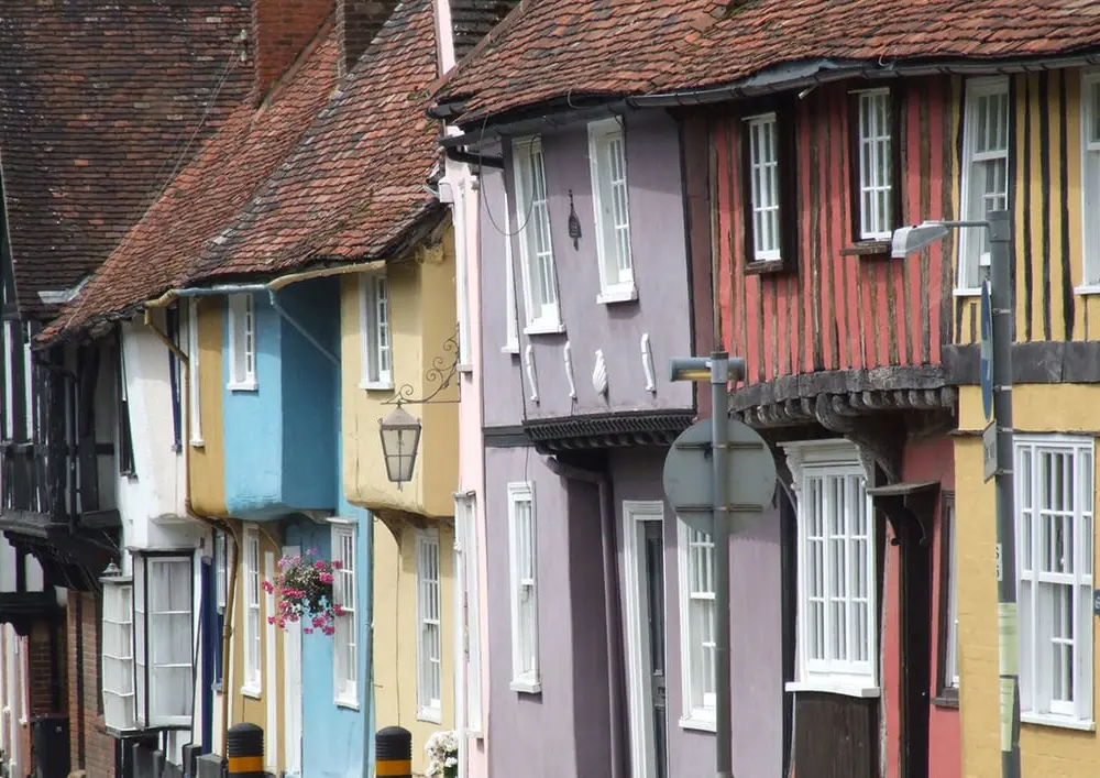 A row of timber-framed houses painted blue, cream, lilac, red and yellow on Castle Street in Saffron Walden.